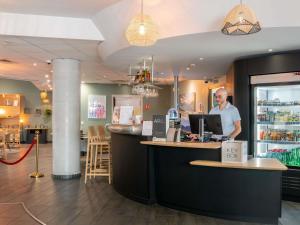 a man standing at a counter in a restaurant at Novotel Suites Cannes Centre in Cannes