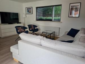 a living room with a white couch and two chairs at Garden House Harry in Zandvoort