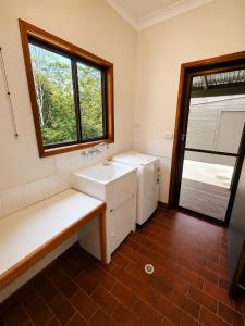 a bathroom with a white sink and a window at Thrums Bush Retreat in Upper Orara +20 photos