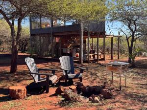 two chairs and a table in front of a house at Mudhouse Zululand in Hluhluwe +39 photos