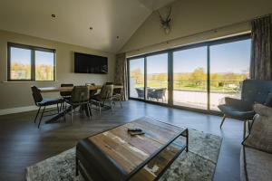a living room with a table and chairs and a large window at The Penthouse @ Carus Green in Kendal
