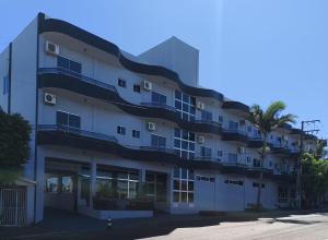 an apartment building with a palm tree in front of it at Florença Hotel in Quedas do Iguacu