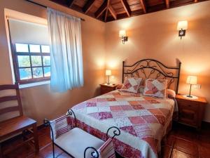a bedroom with a bed with a quilt and a chair at Los Hondos in Garafía