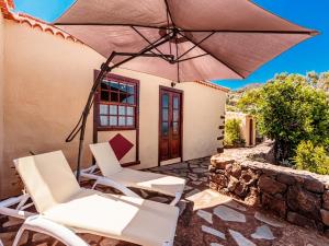 a patio with white chairs and an umbrella at Los Hondos in Garafía
