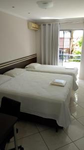 two beds in a hotel room with a window at Florença Hotel in Quedas do Iguacu