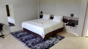 a bedroom with a large white bed with a rug at Florença Hotel in Quedas do Iguacu