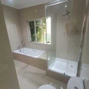 a bathroom with a shower and a tub and a toilet at 75 on Albert Guesthouse in Gqeberha +19 photos