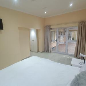 a bedroom with a large bed and a large window at 75 on Albert Guesthouse in Gqeberha
