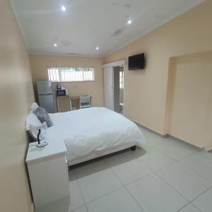 a bedroom with a white bed and a television at 75 on Albert Guesthouse in Gqeberha
