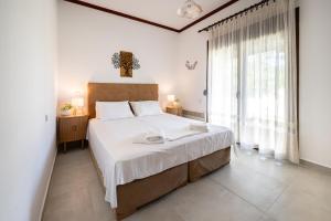 a bedroom with a large bed and a large window at Fourka Garden Villas in Fourka