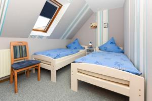 a bedroom with two beds and a chair at Ferienwohnung im Haus Katja in Dunum