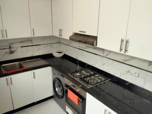 a kitchen with white cabinets and a black counter top at Luxury big House in hearth of Hay Riad with big garden in Rabat +14 photos