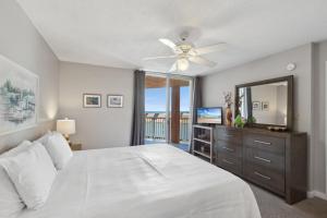 a bedroom with a white bed and a ceiling fan at Buena Vista Condominiums in Gulf Shores