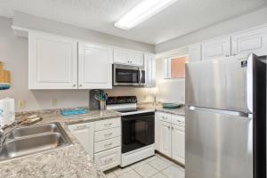 a kitchen with white cabinets and a stainless steel refrigerator at Buena Vista Condominiums in Gulf Shores +40 photos