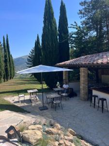 a patio with tables and chairs under a white umbrella at Residenza Castelnovo in Gubbio