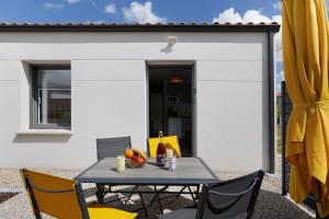 a table and chairs on a patio with a yellow umbrella at Gite Logeraie in Le Boupère