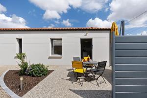 a patio with a table and chairs in front of a house at Gite Logeraie in Le Boupère