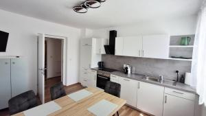 a kitchen with white cabinets and a wooden table at Gästehaus IWANESTAL in Eibesthal