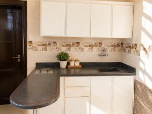 a kitchen with white cabinets and a sink at سويت tolan in Hail