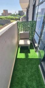 a white chair on a balcony with green grass at Dolphin Homestays in Nairobi