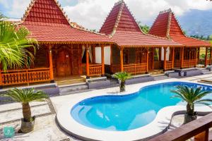 a villa with a swimming pool in front of a building at Instay Villa Dieng Kademangan in Wonosobo