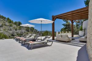 a row of lounge chairs and umbrellas on a patio at Caray - Managed by Almarina Villas in Benissa