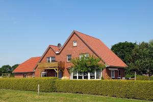 a large brick house with a red roof at Ferienwohnung im Haus Katja in Dunum