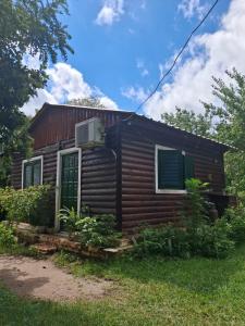 a log cabin with a green door and windows at Cabañas La Fiaca in Los Manantiales