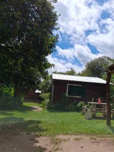 a log cabin with a porch and a tree at Cabañas La Fiaca in Los Manantiales +7 photos