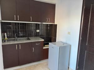 a kitchen with brown cabinets and a sink and a refrigerator at Villa Mare Blue in Ksamil