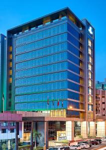wysoki budynek z samochodami zaparkowanymi przed nim w obiekcie Royal Continental Hotel w Dubaju
