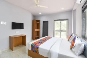a white bedroom with a bed and a tv at FabHotel Ojas Inn in Pune