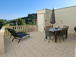 a patio with a table and chairs and an umbrella at Sea View Apartments in Selca