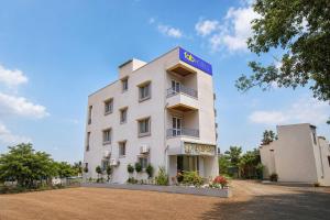 a white building with a blue sign on it at FabHotel Ojas Inn in Pune