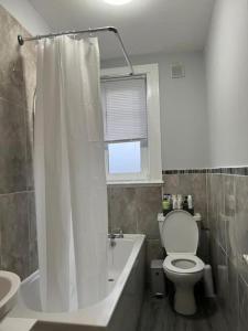 a bathroom with a toilet and a tub and a sink at 3 Bedroom Flat - Sleeps 6 - Free Parking in Kirkcaldy +8 photos