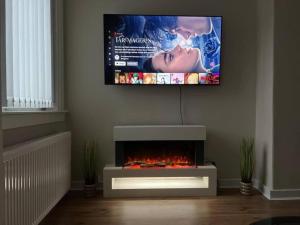 a flat screen tv hanging on a wall with a fireplace at 3 Bedroom Flat - Sleeps 6 - Free Parking in Kirkcaldy