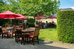 a group of tables and chairs with red umbrellas at Poets House in Ely
