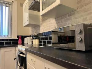 a kitchen with a counter top with a microwave at 3 Bedroom Flat - Sleeps 6 - Free Parking in Kirkcaldy