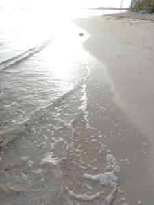 a sandy beach with waves coming in from the ocean at Blue Song Villa in Braco