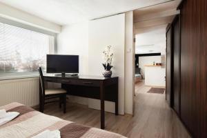 a bedroom with a desk with a television and a bed at Apartman Borievka in Poprad