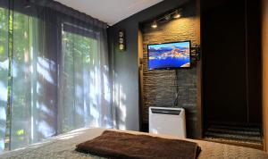 a bedroom with a bed and a tv on a wall at Pirts Rozēni in Saulkrasti