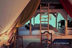 a bedroom with a bunk bed in a tent at Gîte du sorcier - Etat Nature in Magnières