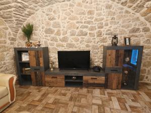 a living room with a tv and a stone wall at Adria Stone House in Grižane