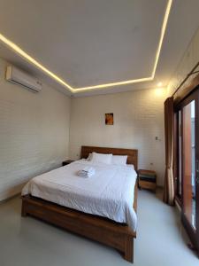 a bedroom with a large bed with white sheets at Pondok Ashanara Sading in Sempidi