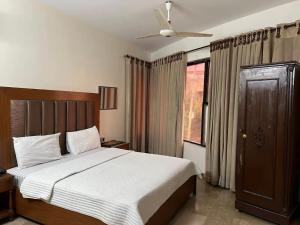 a bedroom with a large bed and a window at Hotel Imperial Karachi in Karachi