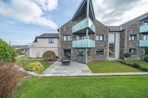 an exterior view of a large stone house with a grass yard at Golf Apartment @ Carus Green in Kendal