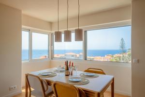 a dining room with a table and chairs and windows at Horizon living Madeira in Caniço
