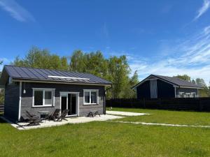 a small house with solar panels on top of it at Dzintarjūras Namiņš 36 in Šķēde