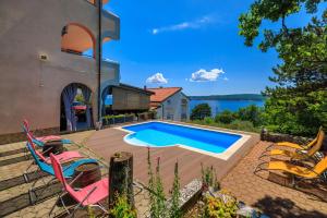 a swimming pool with chairs and a house at Apartments Djusi in Dramalj