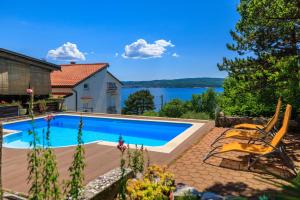 a swimming pool with two chairs and a house at Apartments Djusi in Dramalj